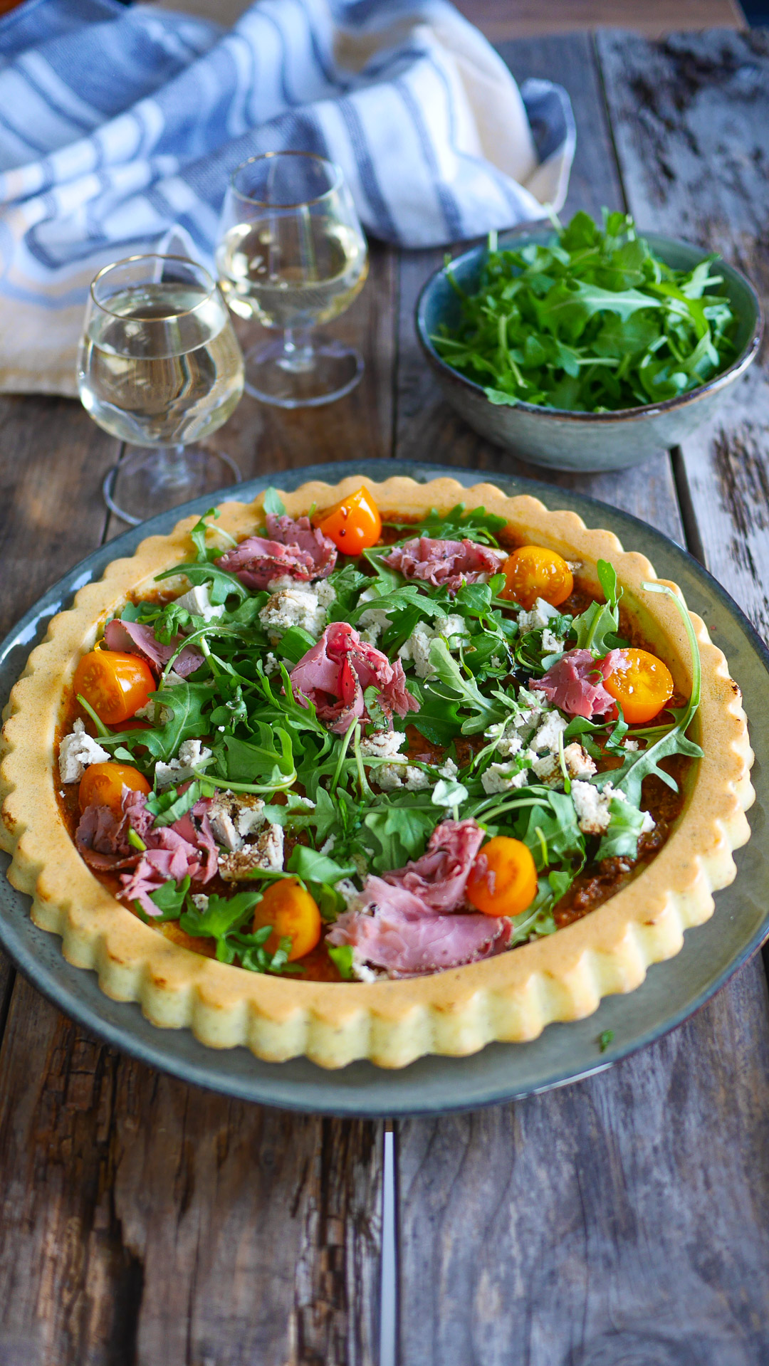 Tarte salée à l'italienne avec une garniture crue : pastrami, roquette, tomate cerises, basilic, feta..